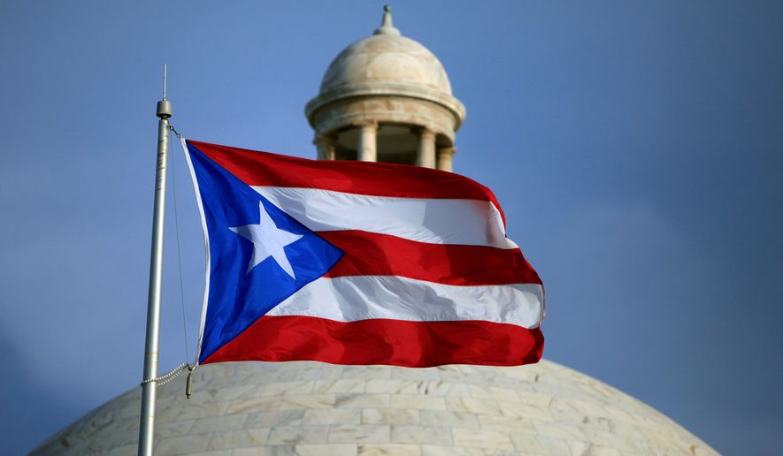 FILE - In this July 29, 2015 file photo, the Puerto Rican flag flies in front of Puerto Rico's Capitol as in San Juan, Puerto Rico. A senior Puerto Ricon official said Tuesday, Feb. 11, 2020, that the island's government has lost more than $2.6 million after falling for an email phishing scam. (AP Photo/Ricardo Arduengo, File)