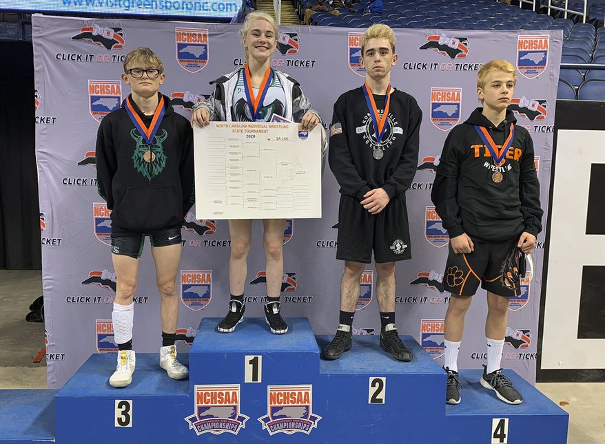 This photo provided by North Carolina High School Athletic Association (NCHSAA) shows Heaven Fitch, center, Luke Wilson, left, and Hunter Fulp, right, and Brandon Ropp, far right, after the state wrestling championships in Greensboro, N.C, on Saturday, Feb. 22, 2020. NCHSAA said on its website that Fitch of Uwharrie Charter became the first female to win one of the association's individual state wrestling championships. She won the 106 pound (48 kg) weight class at the 1A division on Saturday. (North Carolina High School Athletic Association via AP)