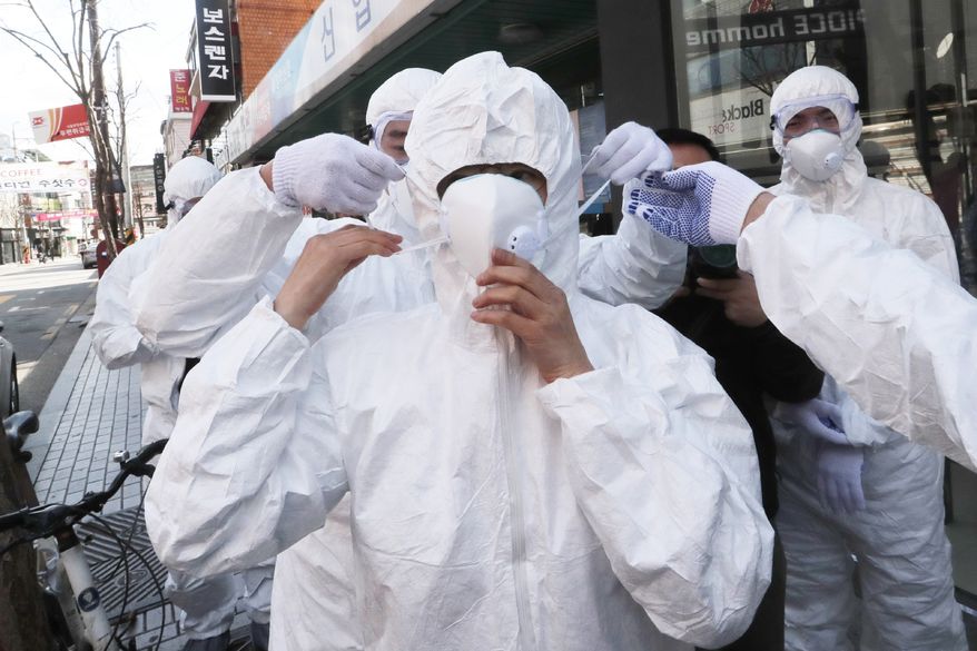 A worker wears a face mask to spray disinfectant as a precaution against the coronavirus at a shopping street in Seoul, South Korea, Thursday, Feb. 27, 2020. South Korea and China each reported hundreds more virus cases Thursday as the new illness persists in the worst-hit areas and spreads beyond borders. (AP Photo/Ahn Young-joon)