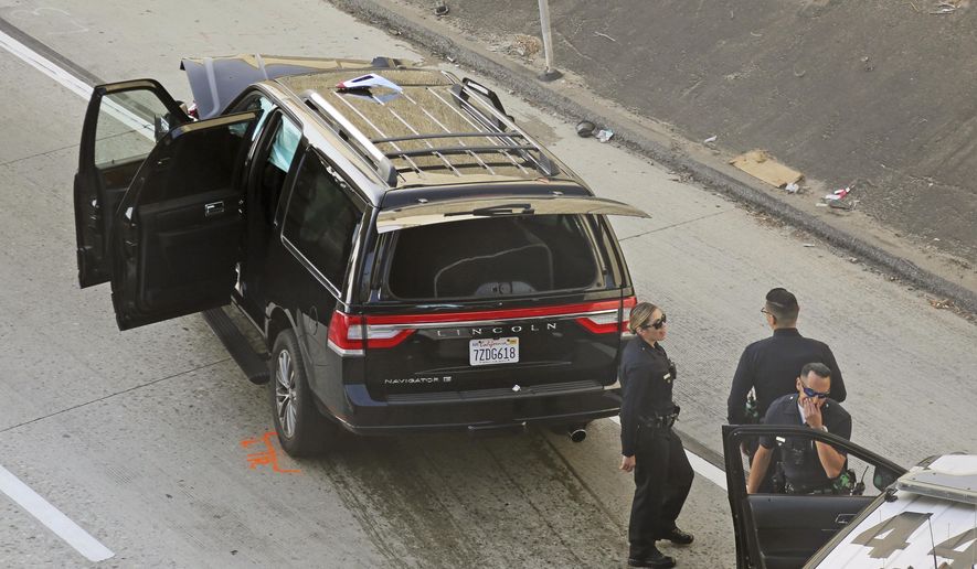 Los Angeles police officers stand after a pursuit of a stolen hearse with with a casket and body inside on Interstate 110 in South Los Angeles Thursday, Feb. 27, 2020. The hearse was stolen from outside a Greek Orthodox church in East Pasadena on Wednesday night. The Los Angeles County Sheriff's Department says one person is in custody. (AP Photo/Reed Saxon)