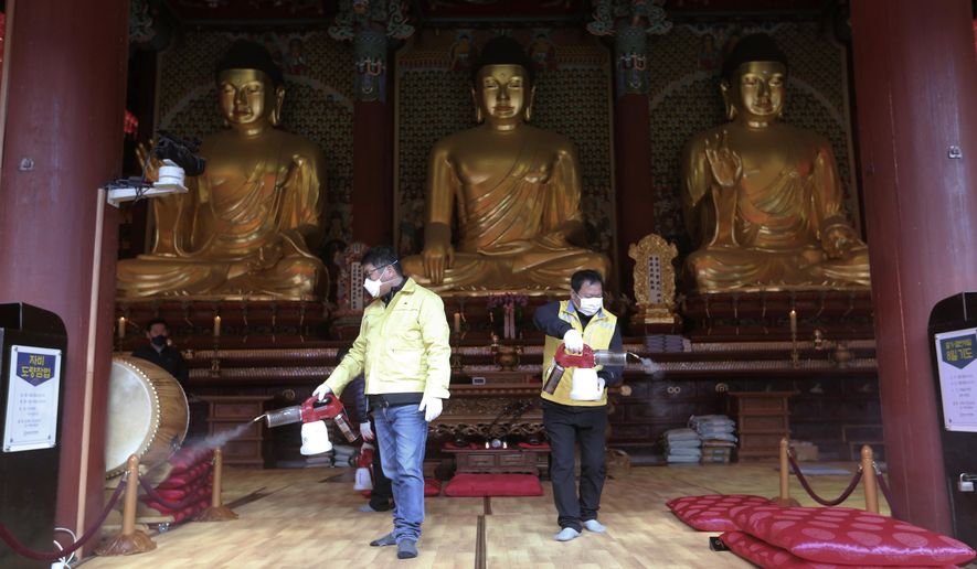 Residents of Jongno-Gu wearing face masks spray disinfectant as a precaution against the coronavirus at the Jogyesa Buddhist temple in Seoul, South Korea, Thursday, Feb. 27, 2020. South Korea and China each reported hundreds more virus cases Thursday as the new illness persists in the worst-hit areas and spreads beyond borders. (AP Photo/Ahn Young-joon)