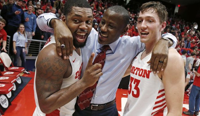 Dayton coach Anthony Grant, center, gives a hug to players Trey Landers, left, and Ryan Mikesell following the team&#x27;s 82-67 win over Davidson in an NCAA college basketball game Friday, Feb. 28, 2020, in Dayton, Ohio. (AP Photo/Gary Landers)