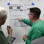 Caucus-goers look over vote numbers at a caucus location at Coronado High School in Henderson, Nev., Saturday, Feb. 22, 2020. (AP Photo/Patrick Semansky)