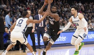 Sacramento Kings forward Harrison Barnes (40) drives to the basket while defended by Memphis Grizzlies guards De&#x27;Anthony Melton (0) and Dillon Brooks (24) during the first half of an NBA basketball game Friday, Feb. 28, 2020, in Memphis, Tenn. (AP Photo/Nikki Boertman)