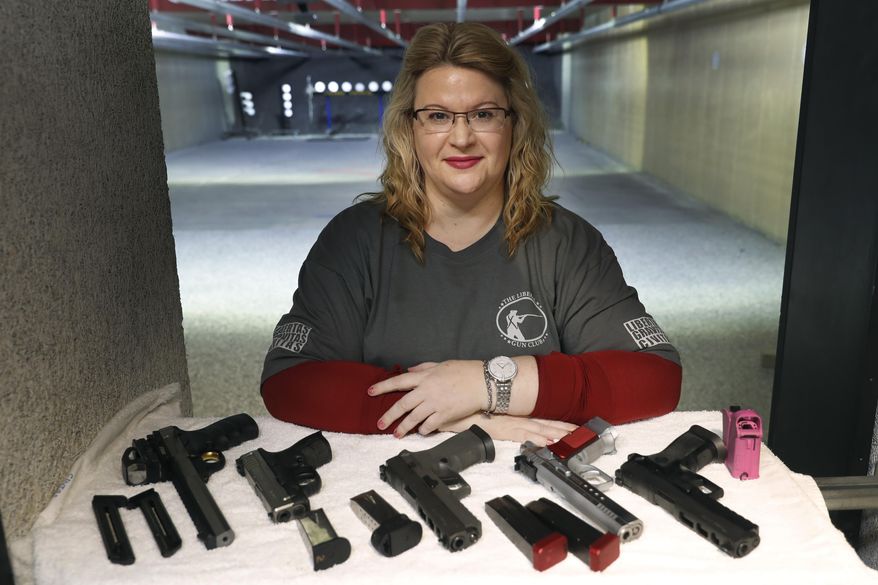 In this Wednesday, Feb. 5, 2020, photo, Kat Ellsworth of Chicago, poses for a portrait with five of the seven guns she owns at the Caliber Tactical Gun Range in Waukegan, Ill. Ellsworth was firmly against firearms and favored gun-control until just a few years ago when she went with a friend to a gun range and discovered a love for firearms and shooting. (AP Photo/Charles Rex Arbogast)
