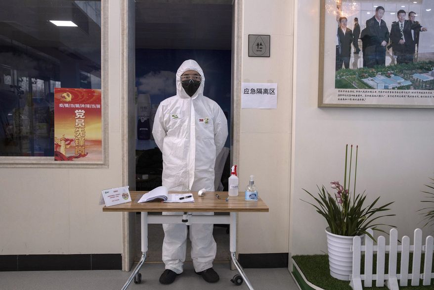 In this Thursday, Feb. 27, 2020, photo, a worker stands near a picture showing Chinese President Xi Jinping visiting the Mengniu dairy factory in Beijing. Reporters were invited to China Mengniu Dairy Co. Ltd. this week to be shown how companies are reviving after anti-virus measures shut down most of the world's second-biggest economy. (AP Photo/Ng Han Guan)
