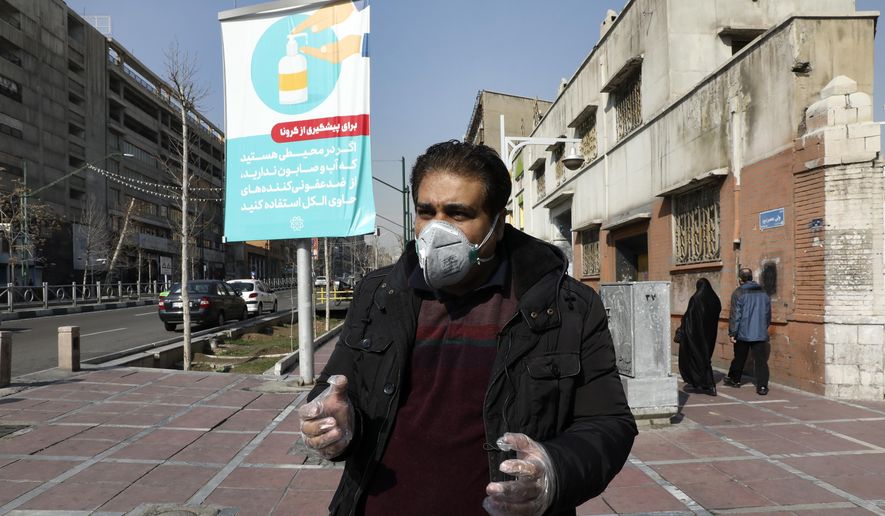 Tehran resident Mohammad Reza Khani, wearing mask and gloves, speaks with The Associated Press in downtown Tehran, Iran, Thursday, Feb. 27, 2020. Amid fear and uncertainty caused by the spread of a new virus, Iranians are taking extra caution to avoid getting infected, as authorities canceled Friday prayers in Tehran, Qom and other cities. The billboard at rear show soap dispenser reading (Farsi) &amp;quot;If you are somewhere with no access to water and soap, use alcohol-based sanitizers.&amp;quot; (AP Photo/Vahid Salemi)