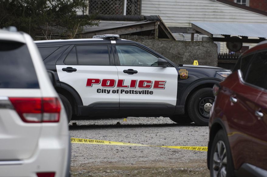 A Pottsville police car is surrounded by police tape and evidence markers at the back of Woody's Bar and Backyard Paradise, in Pottsville, Pa., after an early morning shooting on Saturday, Feb. 29, 2020. Authorities say a shooting outside the eastern Pennsylvania bar sent several people to medical facilities for treatment. (David McKeown/Republican-Herald via AP)