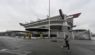 A woman jogs outside San Siro stadium where a Serie A soccer match between AC Milan and Genoa was supposed to take place but was instead postponed to May 13, 2020, in Milan, Italy, Sunday, March 1, 2020. In Lombardy, the hardest-hit region by the spread of the Coronavirus, schools and universities were ordered to stay closed, and sporting events were canceled.(Claudio Furlan/LaPresse via AP)