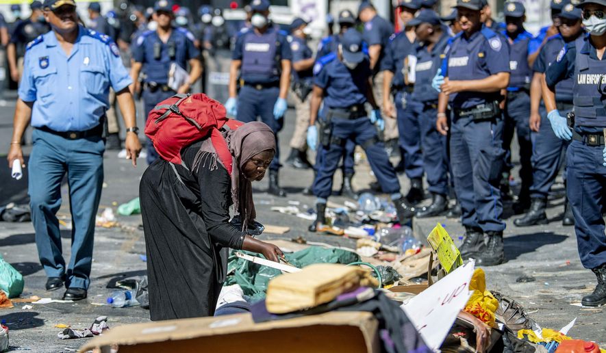 A woman sorts out her belongings, outside the Central Methodist Mission Church in Cape Town, South Africa, Sunday, March 1, 2020 as city officials and police move in to evict them. Hundreds of migrants have been removed from central Cape Town by South African authorities following a months-long stand-off.The migrants removed on Sunday had demanded to be relocated to other countries claiming they had been threatened by xenophobic violence last year. (AP Photo)