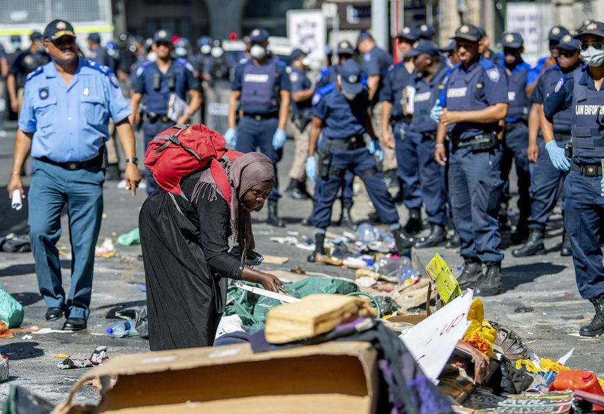 A woman sorts out her belongings, outside the Central Methodist Mission Church in Cape Town, South Africa, Sunday, March 1, 2020 as city officials and police move in to evict them. Hundreds of migrants have been removed from central Cape Town by South African authorities following a months-long stand-off.The migrants removed on Sunday had demanded to be relocated to other countries claiming they had been threatened by xenophobic violence last year. (AP Photo)
