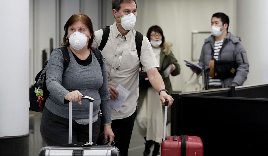 Travelers wear protective mask as they walk through in terminal 5 at O&#x27;Hare International Airport in Chicago, Sunday, March 1, 2020. (AP Photo/Nam Y. Huh)