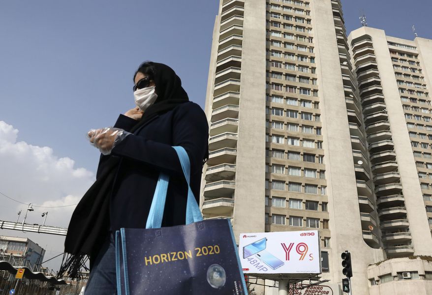 A pedestrian wearing a face mask crosses a street in northern Tehran, Iran, Sunday, March 1, 2020. While the new coronavirus has extended its reach across the world, geographic clusters of infections were emerging, with Iran, Italy and South Korea seeing rising cases. (AP Photo/Vahid Salemi)