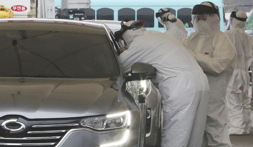 Medical staff wearing protective suits take samples from a driver with symptoms of the coronavirus at a &amp;quot;drive-through&amp;quot; virus test facility in Goyang, South Korea, Sunday, March 1, 2020. The coronavirus has claimed its first victim in the United States as the number of cases shot up in Iran, Italy and South Korea and the spreading outbreak shook the global economy. (AP Photo/Ahn Young-joon)