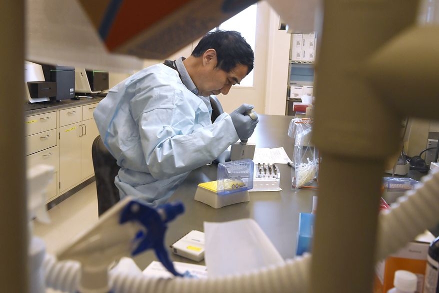 Microbiologist Xiugen Zhang runs a Polymerase Chain Reaction (PCR) test at the Connecticut State Public Health Laboratory, Monday, March 2, 2020, in Rocky Hill, Conn. The Connecticut Department of Public Health has received federal approval from the Centers for Disease Control and Prevention and the Food and Drug Administration to run diagnostic testing for the coronavirus at the department's lab in Rocky Hill. (AP Photo/Jessica Hill)