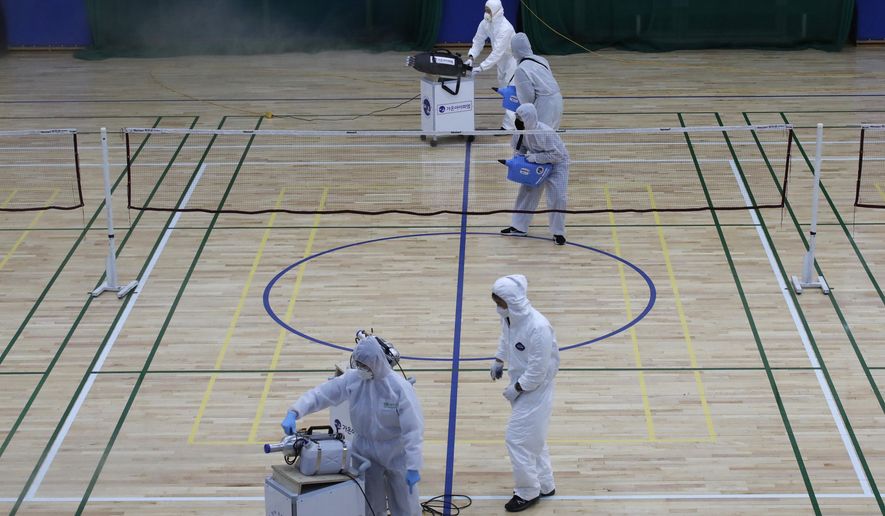 In this Feb. 25, 2020, file photo, workers in protective suits spray disinfectant as a precaution against the COVID-19 at an indoor gymnasium in Seoul, South Korea. As the coronavirus spreads around the world, many events that normally would draw large numbers of people are being canceled or played without fans. (AP Photo/Lee Jin-man, File)