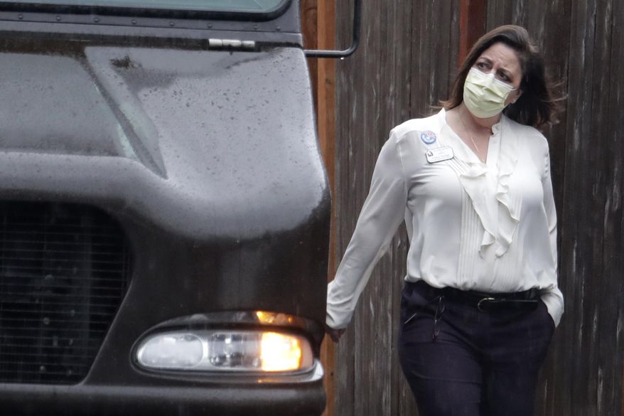 A worker at the Life Care Center in Kirkland, Wash., near Seattle, wears a mask as she walks near a UPS truck during a package delivery, Monday, March 2, 2020. Several of the people who have died in Washington state from the COVID-19 coronavirus were tied to the long-term care facility, where dozens of residents were sick. (AP Photo/Ted S. Warren)