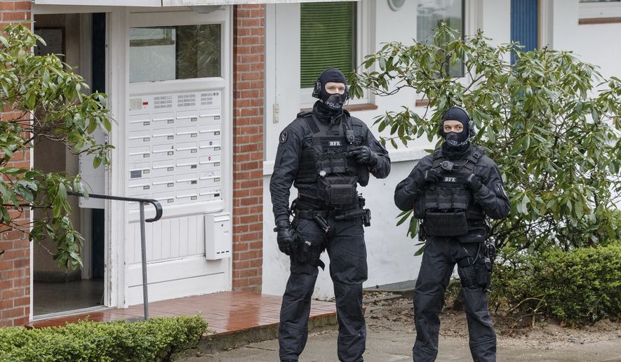 Police officers stay in front of an apartment building in Bad Segeberg, northern Germany, Tuesday, March 3, 2020. German police have raided the homes of 12 people in the German state of Schleswig-Holstein and elsewhere in Germany who are suspected of forming a far-right group that wanted to attack immigrants and foreigners. (Markus Scholz/dpa via AP)