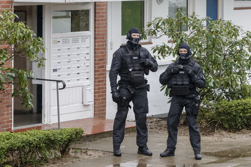 Police officers stay in front of an apartment building in Bad Segeberg, northern Germany, Tuesday, March 3, 2020. German police have raided the homes of 12 people in the German state of Schleswig-Holstein and elsewhere in Germany who are suspected of forming a far-right group that wanted to attack immigrants and foreigners. (Markus Scholz/dpa via AP)