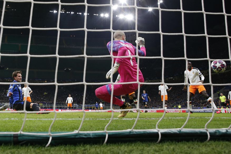 Atalanta's Hans Hateboer, right, scores his side's opening goal during the Champions League round of 16, first leg, soccer match between Atalanta and Valencia at the San Siro stadium in Milan, Italy, Wednesday, Feb. 19, 2020. (AP Photo/Antonio Calanni)