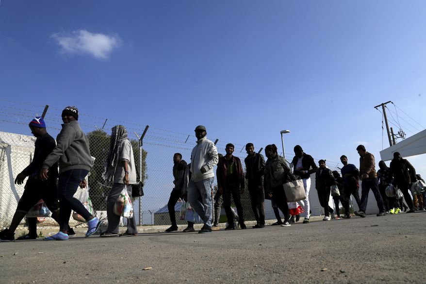 Migrants walk towards to a refugee camp after they come back from the immigration inside a refugee camp in Kokkinotrimithia outside of Nicosia, Cyprus, Tuesday, March 3, 2020. The government of ethnically divided Cyprus is ramping up measures to stem migrant inflows amid fears of a surge of new arrivals following Turkey's decision to open its borders to those seeking to enter Europe illegally. (AP Photo/Petros Karadjias)