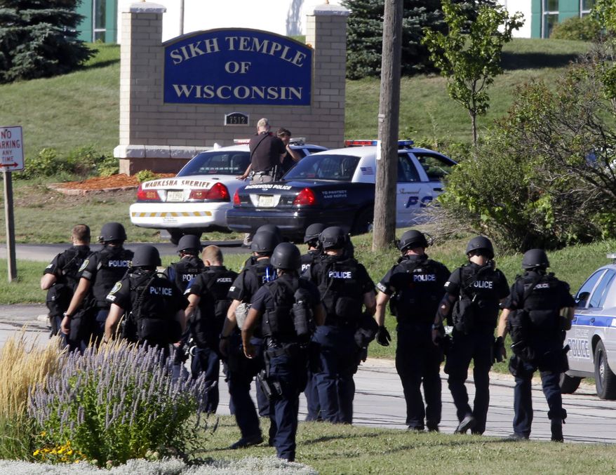 In this Aug. 5, 2012 photo, Police walk near the Sikh Temple of Wisconsin in Oak Creek, Wis., after a shooting. Authorities say a survivor of a 2012 shooting at the suburban Milwaukee Sikh temple that killed six worshipers has died of complications from the head injuries that left him paralyzed. (AP Photo/Jeffrey Phelps, File)