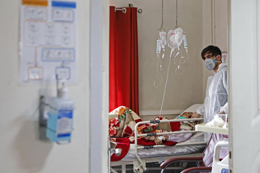 In this Sunday, March 1, 2020, photo, a medic treats a patient infected with coronavirus, at a hospital in Tehran, Iran. A member of a council that advises Iran's supreme leader died Monday after falling sick from the new coronavirus, becoming the first top official to succumb to the illness striking both citizens and leaders of the Islamic Republic. (Ali Shirband/Mizan News Agency via AP)