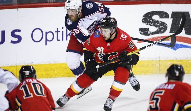Columbus Blue Jackets&#x27; David Savard, , left, scrambles to get past Calgary Flames&#x27; Andrew Mangiapane during the second period of an NHL hockey game, Wednesday, March 4, 2020 in Calgary, Alberta. (Jeff McIntosh/The Canadian Press via AP)