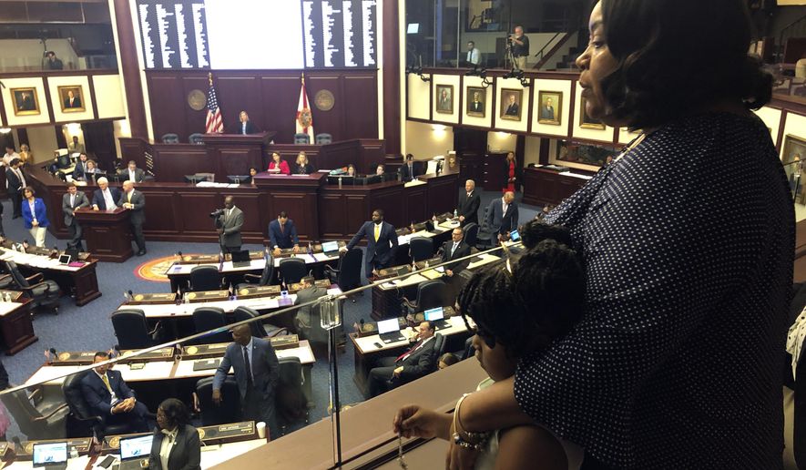 Meralyn Kirkland holds her granddaughter Kaia Rolle as legislaors work on the House floor, Wednesday, March 4, 2020, in Tallahassee, Fla. Florida lawmakers rallied behind a 6-year-old Rolle who was zip-tied at school and arrested last fall, and on Wednesday inserted an amendment into a school safety bill to require authorities to disclose their policies and procedures for arresting children under 10 years old. The scene generated public outrage when footage from a police body camera showed the crying young girl pleading with the arresting officer for "a second chance." (AP Photo/Bobby Caina Calvan)