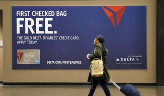 FILE - In this March 24, 2015, file photo, a traveler walks past a sign advertising a Delta Air Lines credit card at Seattle-Tacoma International Airport in SeaTac, Wash. A recent NerdWallet survey found that about a third of Americans plan to travel for 2020 spring break. In addition to earning points, using a travel credit card can provide valuable trip protections, as well as perks like free checked bags or lounge access. (AP Photo/Elaine Thompson, File)