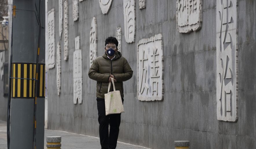 In this Feb. 25, 2020, photo, a resident wearing a mask walks outside a closed school with a mural depicting keywords including at right &amp;quot;Rule of law&amp;quot; in Beijing. Chinese schools turning to online learning during a virus outbreak are running into the country&#39;s ubiquitous and often arbitrary internet censorship. (AP Photo/Ng Han Guan)