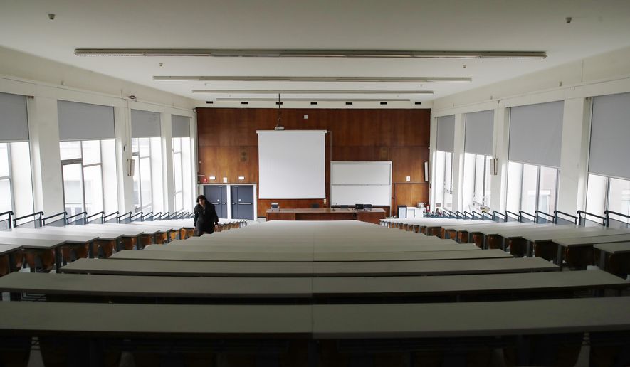 A woman walks in an empty classroom at the Statale University, in Milan, Italy, Thursday, March 5, 2020. Italy&#39;s virus outbreak has been concentrated in the northern region of Lombardy, but fears over how the virus is spreading inside and outside the country has prompted the government to close all schools and Universities nationwide for two weeks. (AP Photo/Antonio Calanni)
