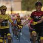 FILE - In this Sunday, July 28, 2019 file photo, Colombia&#39;s Egan Bernal wearing the overall leader&#39;s yellow jersey, left, holds hands with Britain&#39;s Geraint Thomas after winning the Tour de France cycling race in Paris. The team of reigning Tour de France champion Egan Bernal has withdrawn from all races over the next three weeks amid the spread of the new virus outbreak and following the death of one of its sports directors. (AP Photo/Michel Euler, File)