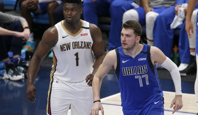 New Orleans Pelicans forward Zion Williamson (1) and Dallas Mavericks guard Luka Doncic (77) watch play during the first half of an NBA basketball game in Dallas, Wednesday, March 4, 2020. (AP Photo/Michael Ainsworth)
