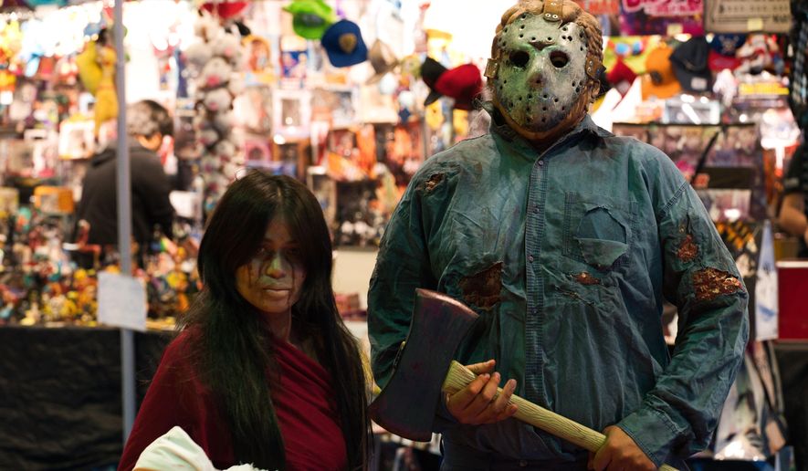 A man dressed as Jason Voorhees from the "Friday the 13th" films stands next to a woman in cosplay at the Middle East Film & Comic Con in Dubai, United Arab Emirates, Thursday, March 5, 2020. The Middle East Film & Comic Con began Thursday night in Dubai, a city of skyscrapers and nightclubs suddenly subdued by the outbreak of the new coronavirus across the region. (AP Photo/Jon Gambrell)