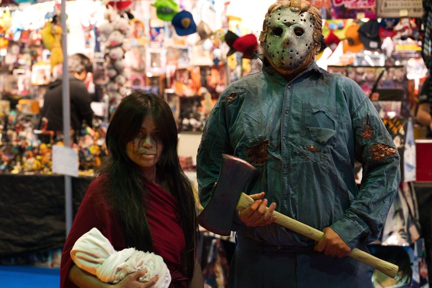 A man dressed as Jason Voorhees from the "Friday the 13th" films stands next to a woman in cosplay at the Middle East Film & Comic Con in Dubai, United Arab Emirates, Thursday, March 5, 2020. The Middle East Film & Comic Con began Thursday night in Dubai, a city of skyscrapers and nightclubs suddenly subdued by the outbreak of the new coronavirus across the region. (AP Photo/Jon Gambrell)