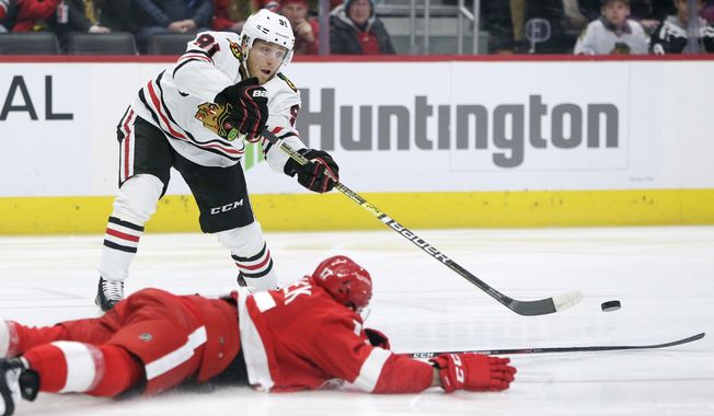 Chicago Blackhawks center Drake Caggiula (91) passes the puck against Detroit Red Wings defenseman Filip Hronek (17) during the first period of an NHL hockey game Friday, March 6, 2020, in Detroit. (AP Photo/Duane Burleson)