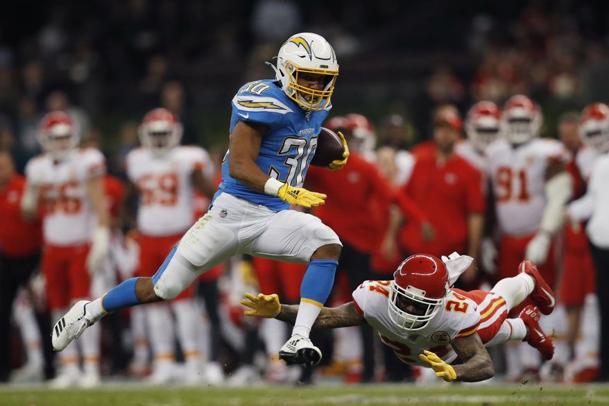 FILE - In this Nov. 18, 2019, file photo, Los Angeles Chargers running back Austin Ekeler, left, gets past Kansas City Chiefs strong safety Jordan Lucas, right, during the first half of an NFL football game in Mexico City. Ekeler’s breakout season with the Los Angeles Chargers has resulted in a contract extension. The running back has agreed to a four-year deal with the Chargers worth #24.5 million, including $15 million guaranteed. Ekeler was slated to be a restricted free agent when the new league year starts on March 18.(AP Photo/Eduardo Verdugo, File)