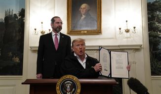 President Donald Trump holds up an $8.3 billion bill to fight the coronavirus outbreak in the U.S., Friday, March 6, 2020 at the White House in Washington after signing, as Department of Health and Human Services Secretary Alex Azar, looks on.  The legislation provides federal public health agencies with money for vaccines, tests and potential treatments and helps state and local governments prepare and respond to the threat. The rapid spread of the virus has rocked financial markets, interrupted travel and threatens to affect everyday life in the United States.   (AP Photo/Evan Vucci)