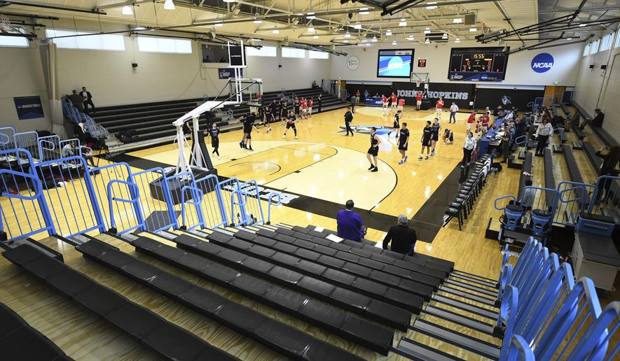 Yeshiva University players, foreground, warm up in a mostly empty Goldfarb Gymnasium at Johns Hopkins University before playing against Worcester Polytechnic Institute in a first-round game at the men's Division III NCAA college basketball tournament, Friday, March 6, 2020, in Baltimore, The university held the tournament without spectators after cases of COVID-19 were confirmed in Maryland. (AP Photo/Terrance Williams)