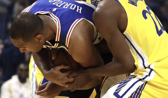 Philadelphia 76ers&#39; Al Horford, left, keeps the ball from Golden State Warriors&#39; Andrew Wiggins (22) in the first half of an NBA basketball game Saturday, March 7, 2020, in San Francisco. (AP Photo/Ben Margot)
