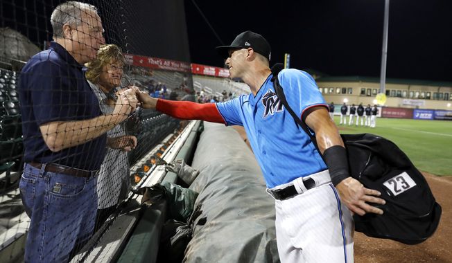 Miami Marlins&#x27; Corey Dickerson, right, greets family friends Duane Allred, left, and his wife, Lynda Allred, of Brookhaven, Miss., prior to a spring training baseball game against the Washington Nationals, Friday, March 6, 2020, in Jupiter, Fla. (AP Photo/Julio Cortez)