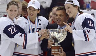 FILE - In this April 9, 2013, file photo, United States&#x27; Kacey Bellamy, Julie Chu and Meghan Duggan, from left, stand with IIHF president Rene Fasel as they are presented with the trophy after the U.S. team defeated Canada 3-2 in the gold medal game at the women&#x27;s ice hockey world championships in Ottawa, Ontario. The women’s world hockey championships in Canada have been canceled because of the new coronavirus. International Ice Hockey Federation President René Fasel tells The Associated Press the decision was made by conference call Saturday, March 7, 2020. (Sean Kilpatrick/The Canadian Press via AP, File)
