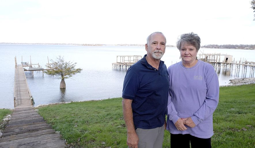 In this undated photo, Paul and Linda Banchetti pose on the shoreline of their property overlooking Eagle Lake in Vicksburg, Miss. Like many other residents in the small community that borders the lake’s eastern shore, the Banchettis have made Eagle Lake their home, and they built it with the potential threat of a flood in mind. (Courtland Wells/The Vicksburg Post via AP)