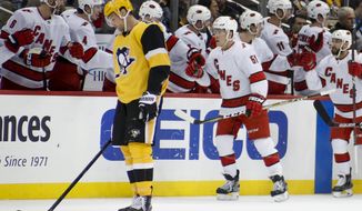 Pittsburgh Penguins&#x27; Brian Dumoulin, left, skates to the bench as Carolina Hurricanes&#x27; Jake Gardiner (51) is greeted by teammates after giving his team the lead with a goal during the second period of an NHL hockey game, Sunday, March 8, 2020, in Pittsburgh. (AP Photo/Keith Srakocic)