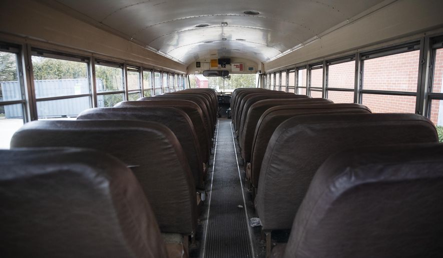 A school bus sits vacant while parked at Saint Raphael Academy in Pawtucket, R.I., Friday, March 6, 2020, as the school remains closed following a confirmed case of the coronavirus. As a growing number of schools across the United States close their doors because of the coronavirus, officials are weighing whether to shut down entirely or move classes online, which could leave behind the many students who don&#39;t have computers, home internet access or parents with flexible work schedules. (AP Photo/David Goldman)