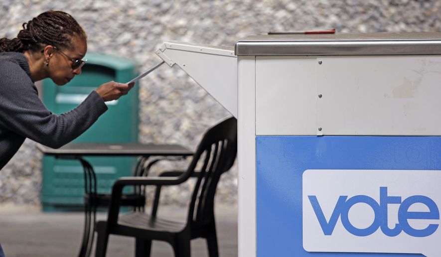 FILE - In this Aug. 2, 2018 file photo, Eudora Carter inserts her ballot into a drop-off voting box in Seattle. Washington is among half a dozen states in the Democratic presidential primary spotlight on Tuesday, March 10, 2020. (AP Photo/Elaine Thompson, File)