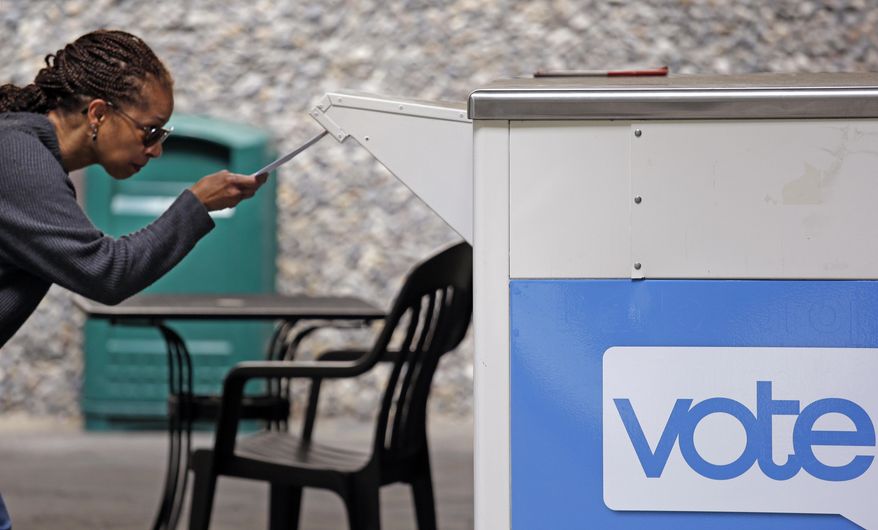 FILE - In this Aug. 2, 2018 file photo, Eudora Carter inserts her ballot into a drop-off voting box in Seattle. Washington is among half a dozen states in the Democratic presidential primary spotlight on Tuesday, March 10, 2020. (AP Photo/Elaine Thompson, File)