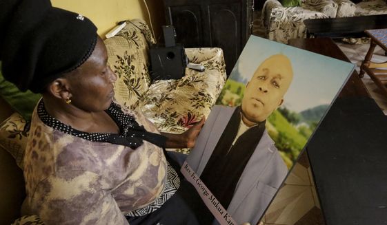In this photo taken Thursday, Feb. 27, 2020, Ruth Kageche, whose brother Rev. George Mukua Kageche, a priest based in Italy, perished on the ill-fated Ethiopian Airlines flight ET302 in 2019, holds a portrait him during an interview with The Associated Press in Nairobi, Kenya. The year since the crash of an Ethiopian Airlines Boeing 737 Max has been a journey through grief, anger and determination for the families of those who died, as well as having far-reaching consequences for the aeronautics industry as it brought about the grounding of all Boeing 737 Max 8 and 9 jets, which remain out of service. (AP Photo/Khalil Senosi)