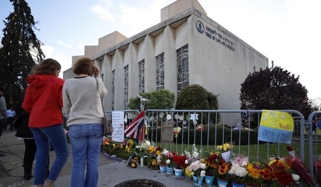 This Oct. 27, 2019 file photo shows passers by pausing outside the Tree of Life synagogue in Pittsburgh on the first anniversary of the shooting at the synagogue, that killed 11 worshippers. Nearly $5.5 million that poured in from donors after the 2018 attack is being distributed according to a plan outlined Monday by Jewish groups. (AP Photo/Gene J. Puskar, File)  **FILE**